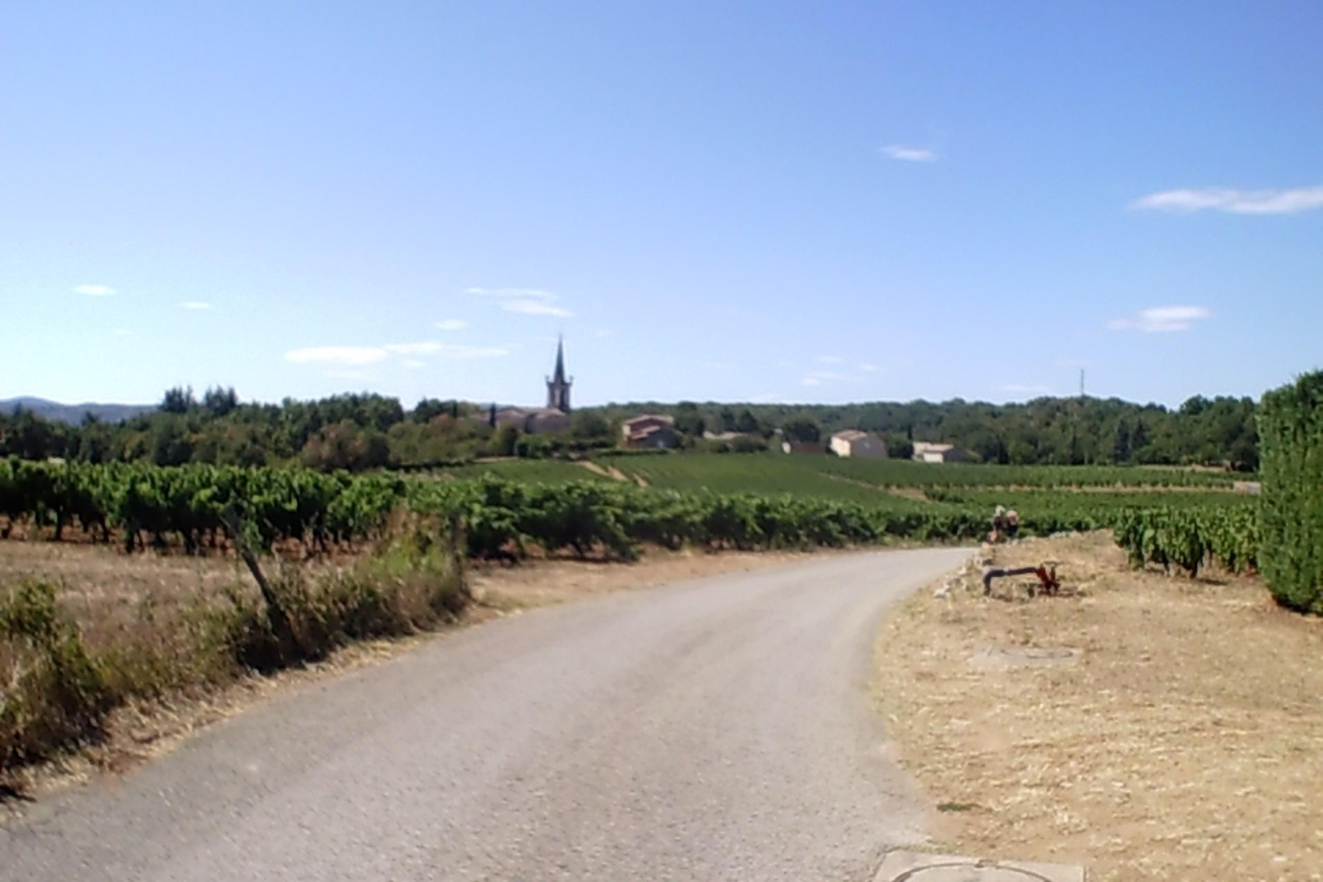 Man sieht einen Weg zu einem Dorf mit Kirche